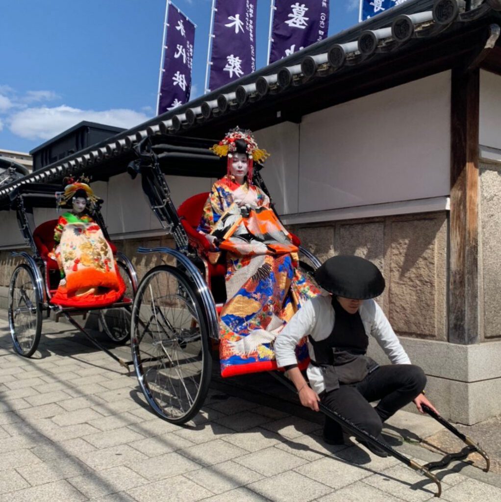 人力車に舞妓さんを乗せて引っ張っている俥夫